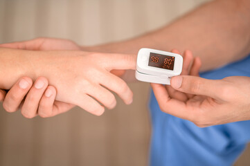 Experienced doctor measuring the oxygen saturation in the blood - obrazy, fototapety, plakaty
