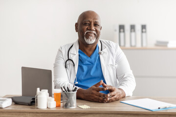 Portrait of smiling doctor looking at camera sitting at desk