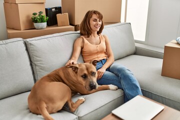 Young caucasian woman hugging dog sitting on sofa at home