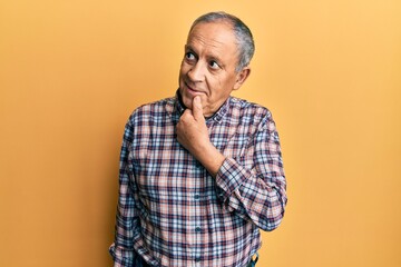 Handsome senior man with grey hair wearing casual shirt with hand on chin thinking about question, pensive expression. smiling with thoughtful face. doubt concept.