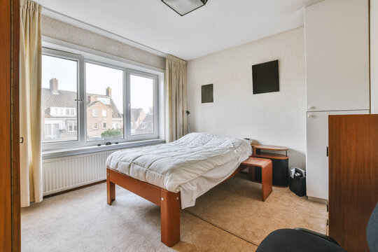 Bedroom interior with bed and commode near big windows