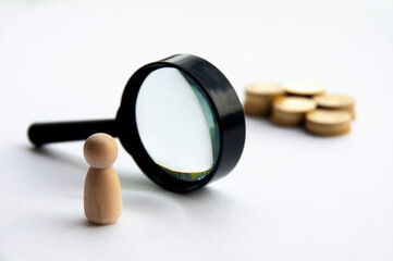 Fototapeta premium Wooden doll looking through magnifying glass for wealth. Copy space.