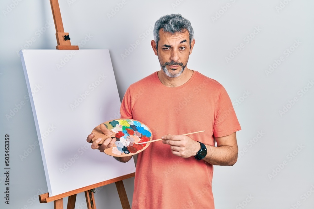 Sticker handsome middle age man with grey hair standing drawing with palette by painter easel stand skeptic 