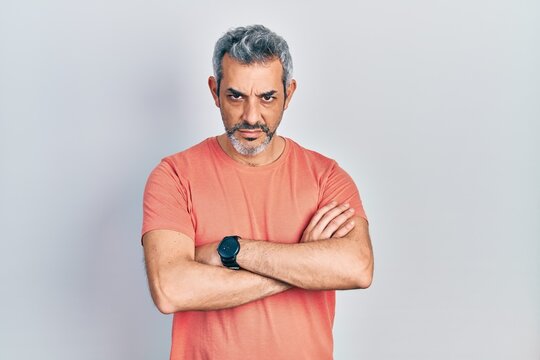 Handsome middle age man with grey hair wearing casual t shirt skeptic and nervous, disapproving expression on face with crossed arms. negative person.