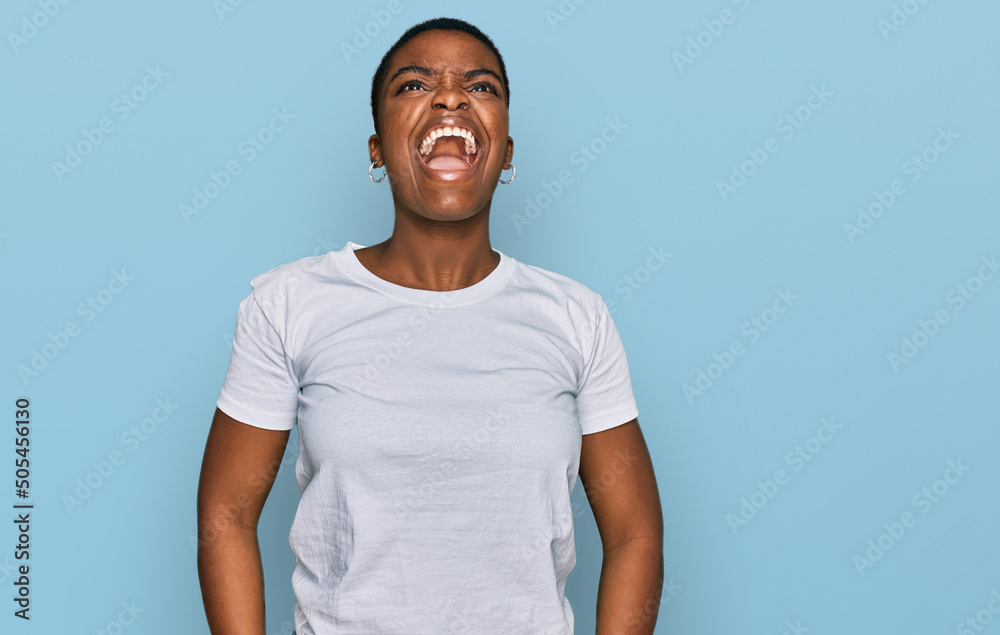 Canvas Prints Young african american woman wearing casual white t shirt angry and mad screaming frustrated and furious, shouting with anger. rage and aggressive concept.