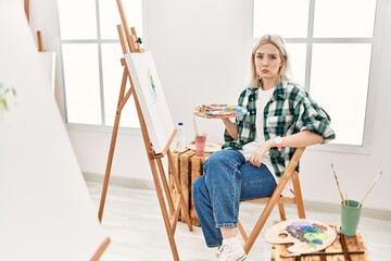 Young artist woman painting on canvas at art studio depressed and worry for distress, crying angry...