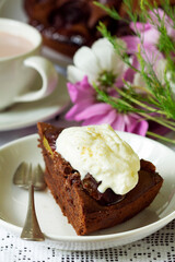 Chocolate plum cake with whipped cream, served with cocoa. Rustic style.