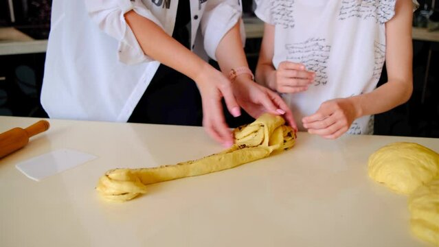 mom and daughter twist the dough with chocolate for baking kraffin