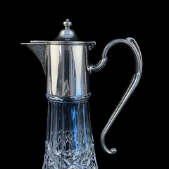 antique crystal decanter with silver neck. vintage drink decanter on black isolated background