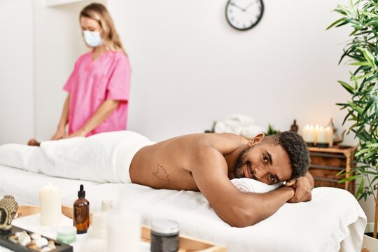Masseur woman make legs massage to african american man at beauty center.