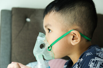 Selective focus picture of a boy using home nebulizer machine for treating asthma, bronchitis and...