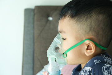 Selective focus picture of a boy using home nebulizer machine for treating asthma, bronchitis and...