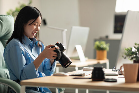 Portrait Of Asian Woman Holding Photo Camera Looking At Screen