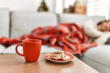Middle age hispanic woman sleeping lying on the sofa by christmas tree at home.