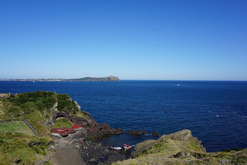Beautiful natural high land with small houses down on the sea view under clear sky
