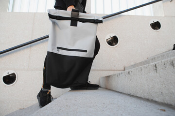 Person carrying backpack with roll top on the stairs 