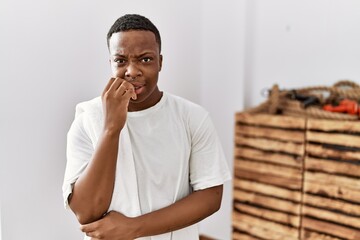 Young african man wearing sportswear and towel looking stressed and nervous with hands on mouth biting nails. anxiety problem.