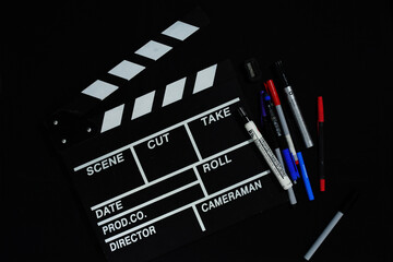 Clapperboard and stationery on black background