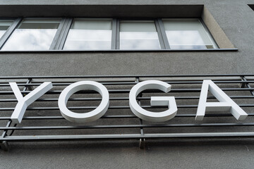 Obraz premium Yoga letters hanging on the wall, big white letters, a sign on the street, a meditation hall designation, printed letters, a day sign.