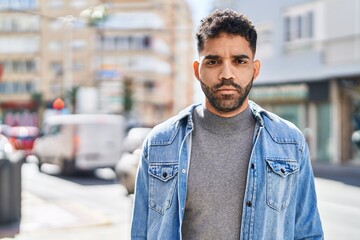 Young hispanic man with relaxed expression standing at street