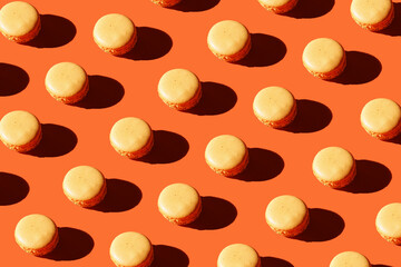 Hard light pattern of an orange macaron pastry on bright orange background