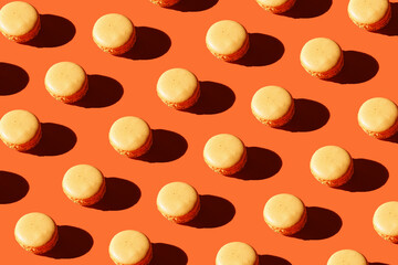 Hard light pattern of an orange macaron pastry on bright orange background
