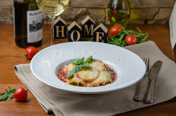 Italian food recipe. Dinner with classic lasagna Bolognese with bechamel sauce, parmesan cheese, basil and tomatoes, on wooden table. Italian restaurant menu