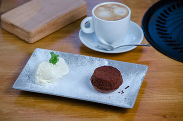 Delicious fresh fondant with vanilla ice cream and latte on wooden table
