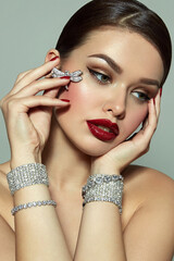 A beautiful, luxurious young girl with green eyes and bright makeup sits in shining jewelry....