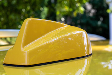 Yellow aerodynamic shark fin style antenna with the reflection of trees