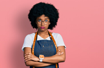 Young african american woman dressmaker designer wearing atelier apron skeptic and nervous,...