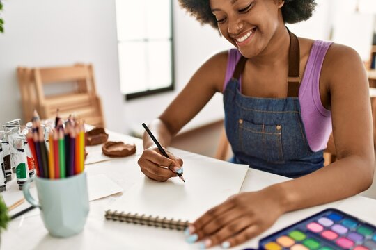 Young african american woman smiling confident drawing sitting on table at art studio