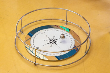 Long exposure photography  of a Foucault pendulum swinging on a compass rose. The pendulum is...