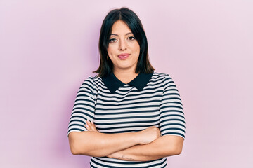 Fototapeta premium Young hispanic woman with arms crossed gesture relaxed with serious expression on face. simple and natural looking at the camera.