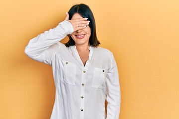 Young hispanic woman wearing casual clothes smiling and laughing with hand on face covering eyes for surprise. blind concept.