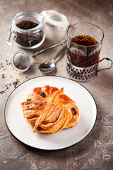 Sweet pies or buns made from yeast dough on platter and glass of tea