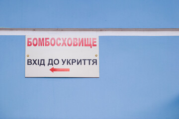 Signboard with inscription in Ukrainian - Bombproof Shelter. Refuge entrance. Air raid warning. Emergency sign. Russia-Ukraine War 2022.