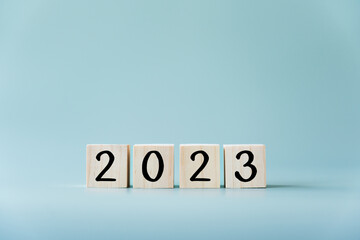 Year 2023 in wooden toy blocks and light blue background. Number in cubes concept of the year 2023.