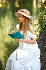 Beautiful lady in a white dress takes some notes on the nature