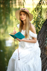 Beautiful lady in a white dress takes some notes on the nature