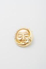 Metallic golden brooch in shape of sun and moon with faces. Spiritual esoteric symbol, astrological boho sign, pin on white background, bijouterie, jewelry