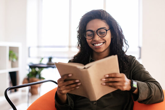 Smiling black woman in glasses reading book