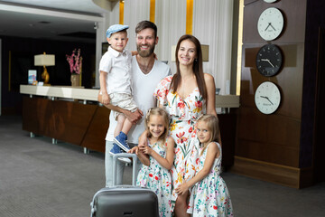 Happy family with luggage near reception desk in hotel