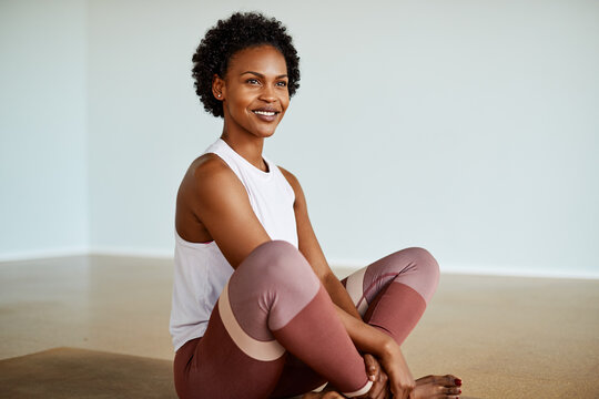 Smiling young woman sitting on a yoga mat