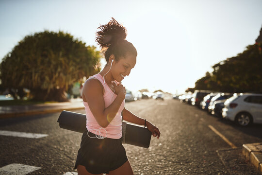 Smiling woman walking to her yoga class listening to music