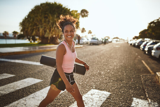 Sporty woman smiling enthusiastically while walking to yoga class