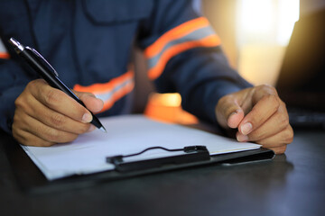 An industrial or shipping inspector auditor supervisor in a reflective jacket is writing a pen on a...