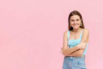 Obraz premium Attractive dark-haired girl in a bright summer outfit smiles with copy space. Positive smiling woman posing on pink background