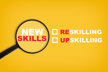 New skills written on yellow paper with magnifying glass. Development concept and reskilling and up skilling idea