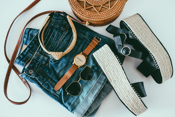 Women's summer clothes collage on white, flat lay. Woven sandals, rattan bag, watch, shorts, sunglasses top view